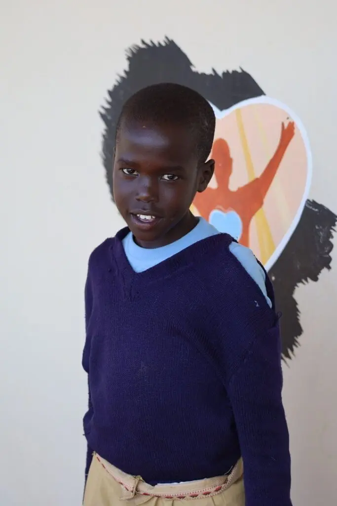 A young boy standing in front of a wall.