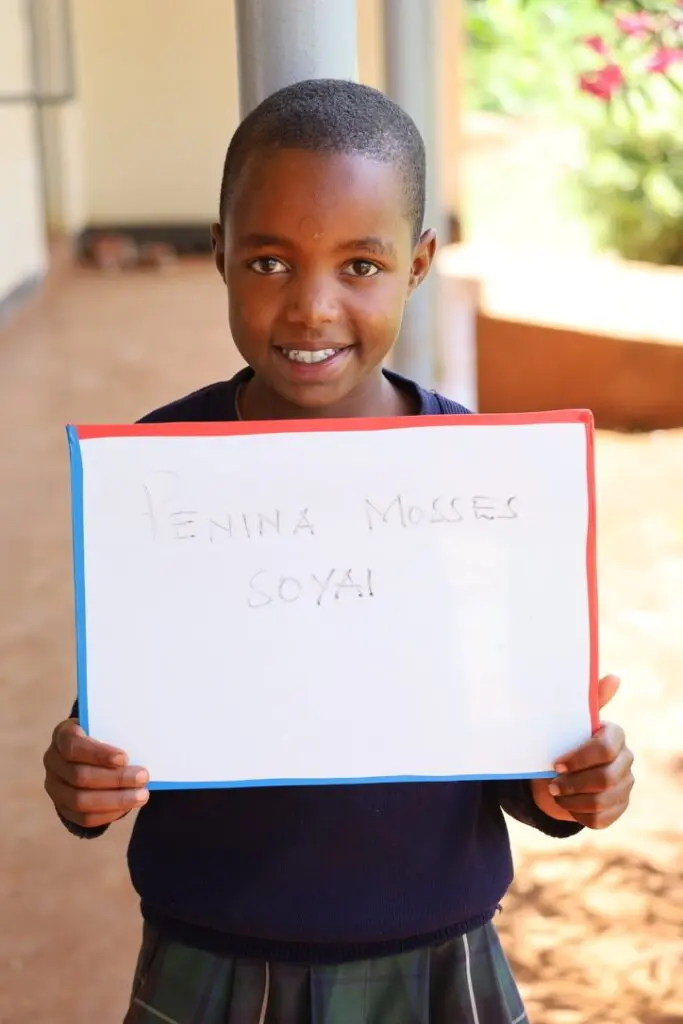 A young boy holding up a white board.