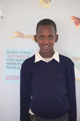 A young boy standing in front of a wall.