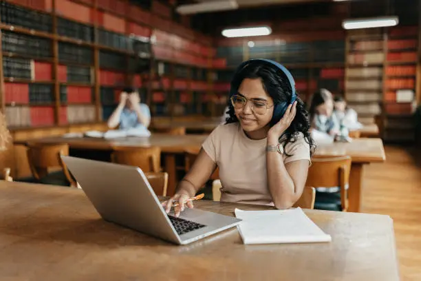 Student using laptop and headphones in library