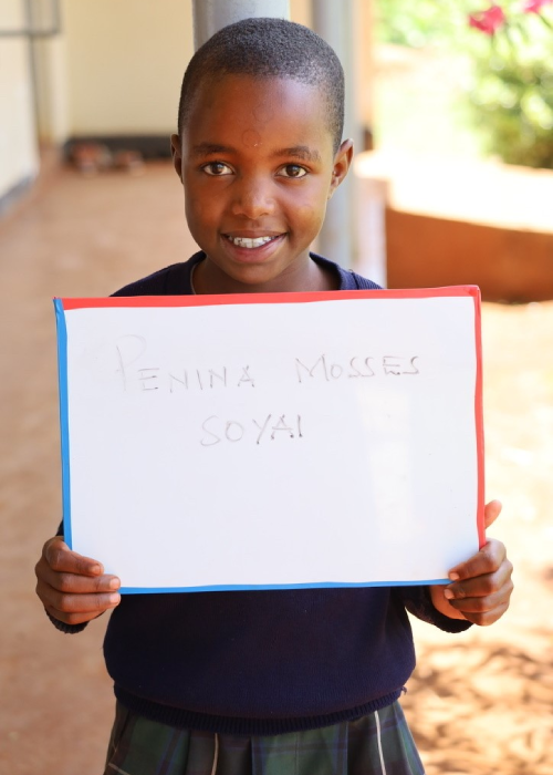 A young boy holding up a sign that says " lesotho mission royal ".