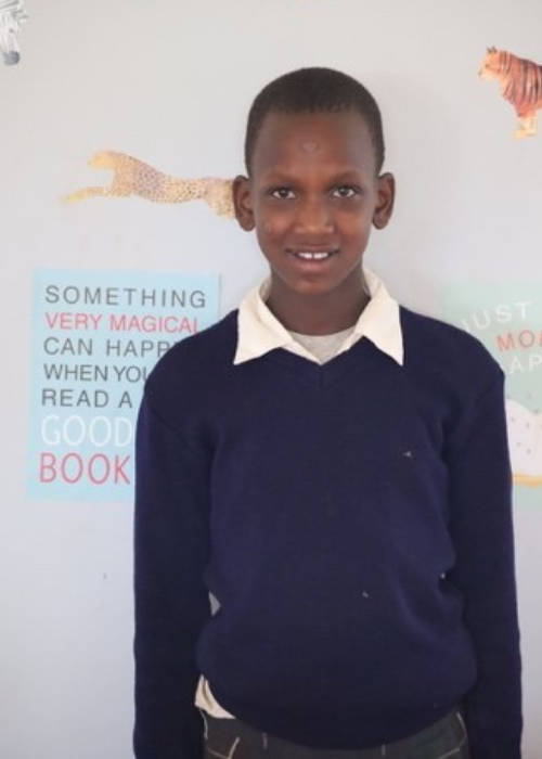 A young boy standing in front of a wall.