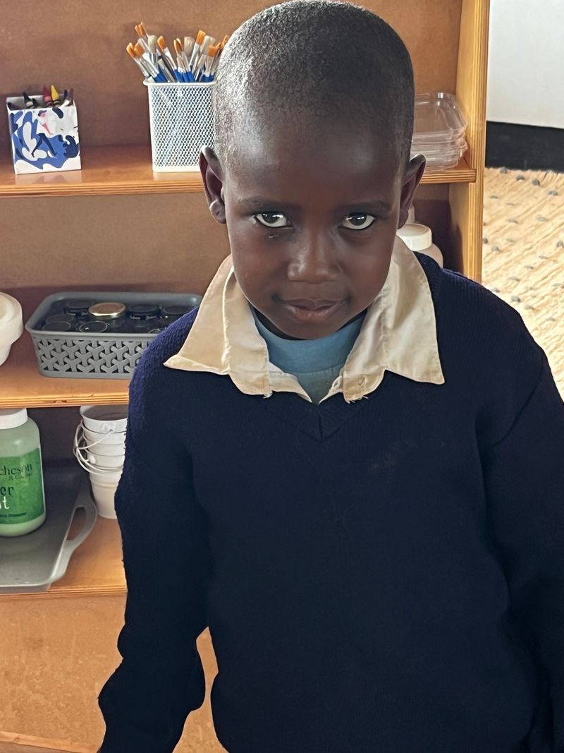 A young boy standing in front of shelves.