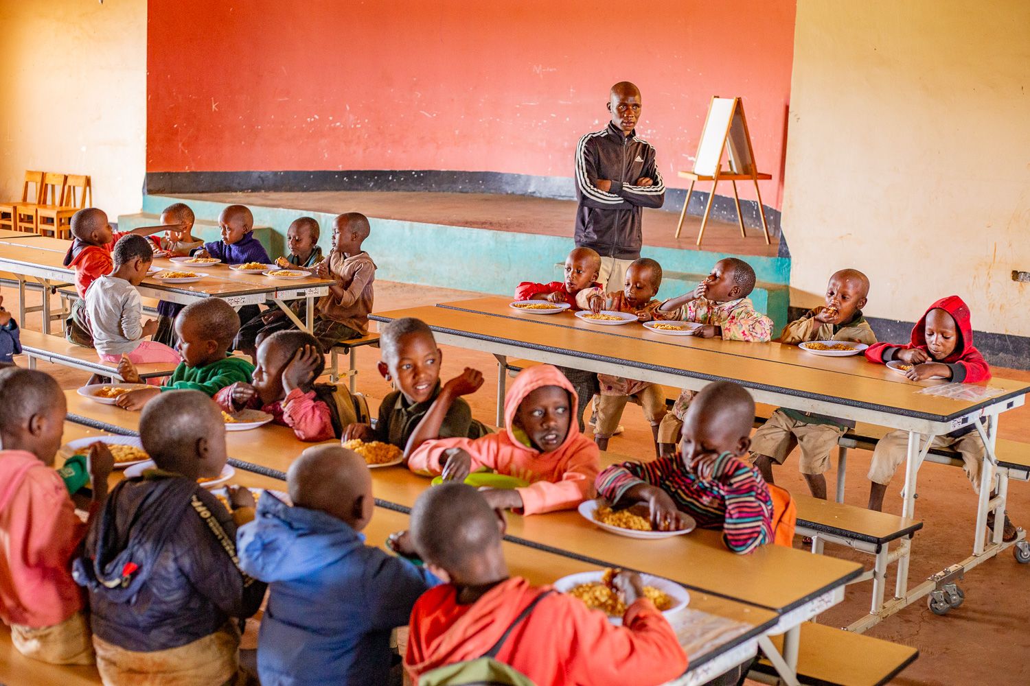 A group of children sitting at tables in front of an adult.