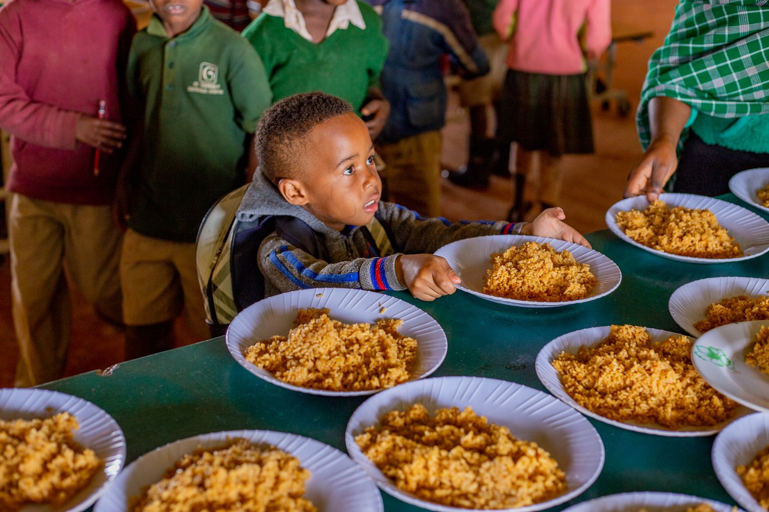 A child sitting at the table with many bowls of food.